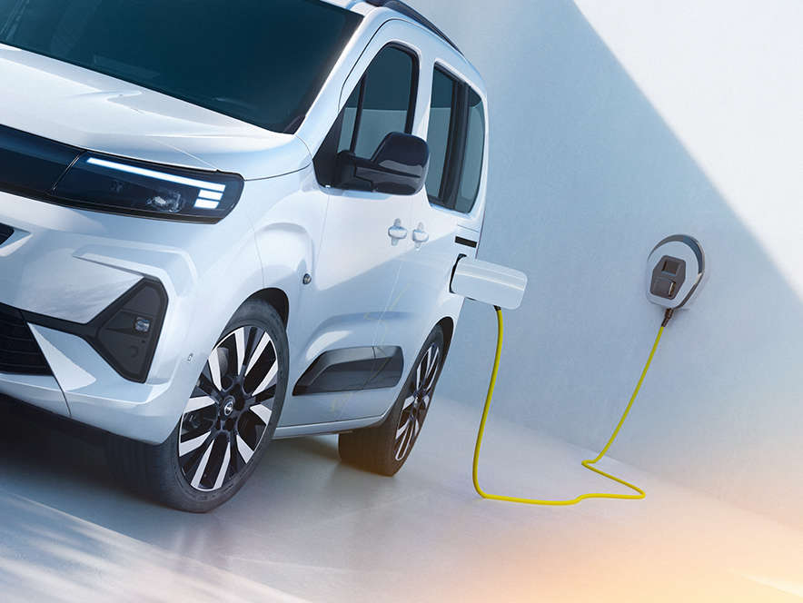 Вигляд спереду на білий Opel Combo Electric, що заряджається від зарядного пристрою для електромобілів